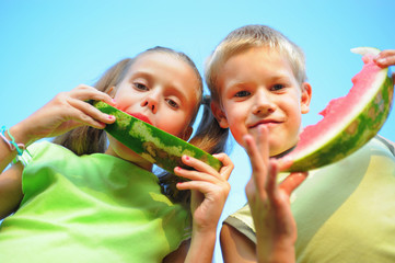 Young girl and boy eating watermelon