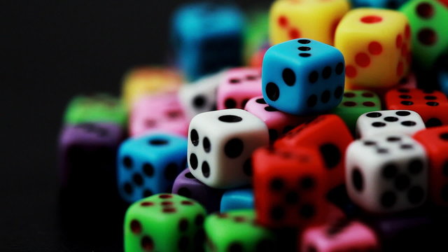 many colorful dice rotate on black, close-up