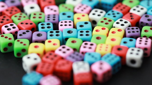 many colorful dice rotate on black, close-up
