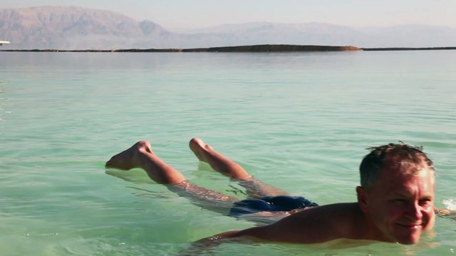 Man relaxed splashing in the water from the Dead Sea.