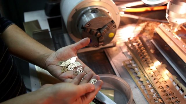 Handful of gold pendants lies in palm, man sorting them