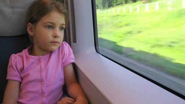 Girl looks through window in moving train, time lapse