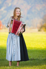 Akkordeonspielerin stehend auf gr&uuml;ner Wiese im Herbst