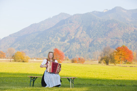 Bergpanorama im Herbst mit Akkordeonspielerin