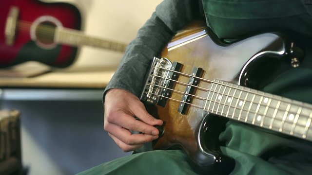 italian craftsman in workshop playing custom bass guitar