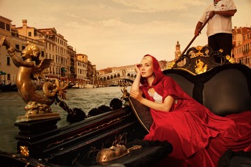Beautifiul woman in red cloak riding on gandola - obrazy, fototapety, plakaty