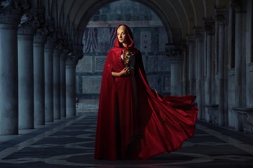 Naklejka premium Beautifiul woman in red cloak outdoors