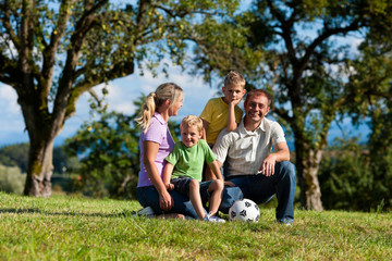 Familie mit Kindern und Fußball auf einer Wiese