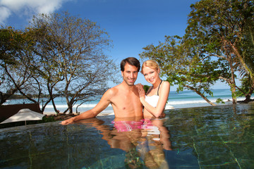 Cheerful couple swimming in resort pool