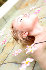 Obraz na płótnie Canvas Piękna kobieta kąpiel w basenie z kwiatów frangipani