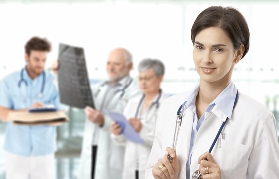 Mid-adult female doctor medical team in background