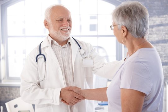 Mature doctor and senior patient shaking hands