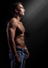 young muscular man on black background
