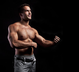 young muscular smiling man on black background - obrazy, fototapety, plakaty