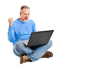 Successful businessman sitting on the floor with a laptop