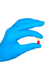 Hand in blue rubber glove holds pill isolated on white backgroun
