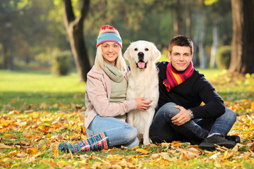 Fototapeta premium Smiling young man and woman hugging a labrador retreiver dog