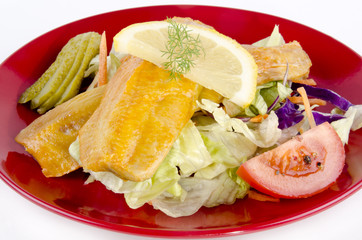 geräucherter Bückling mit Salat und Zitrone auf einem Teller