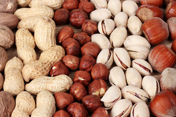 nutmeg, peanuts, hazelnuts and almonds on wooden background