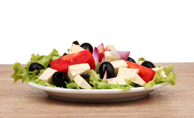 Tasty greek salad on plate on wooden table on white background