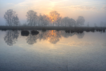 Fototapeta premium Rising sun above a frozen lake