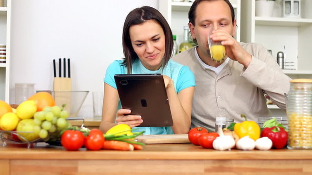 Young happy couple with tablet computer by the table in kitchen