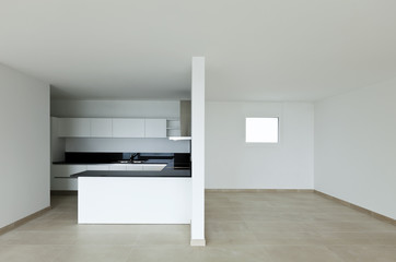 Interior of an empty apartment not yet furnished. You can see two distinct spaces, the kitchen and the dining room.  New apartment, kitchen view