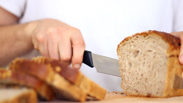 Male hands slicing wholegrain bread, slow motion, steadicam shot