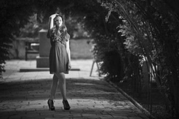 Monochrome image of a sad young woman standing alone in garden