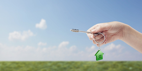 Hand holding key with a keychain in the shape of the house