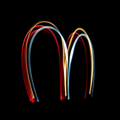 Letter M made from brightly coloured neon lights