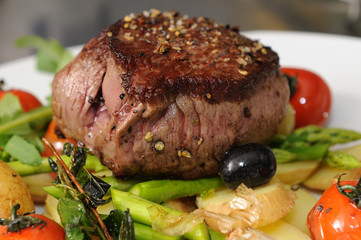 Steak mit Salat - auf grünem Spargel und Kartoffelscheiben
