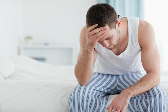 Ill Man Sitting On His Bed