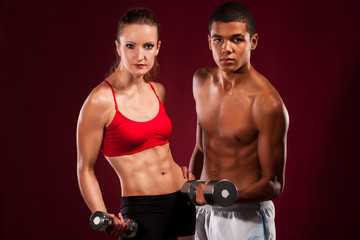 Fototapeta na wymiar strong young couple working out with dumbbells