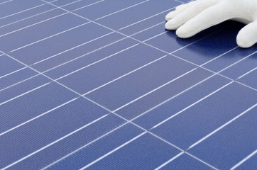 Hand mit weissem Handschuh vor Solarzellen