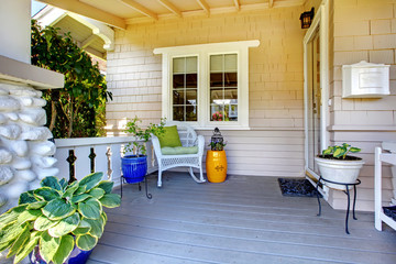 Covered entrance porch with plants and chair.
