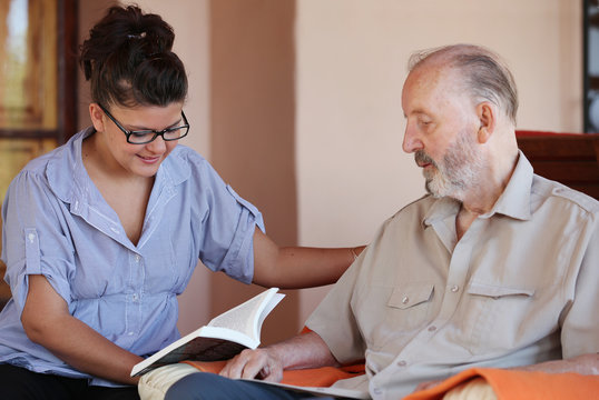 Carer Reading To Senior