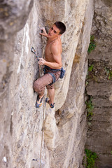 Rock climber fastening rope to quick-draw and looking up