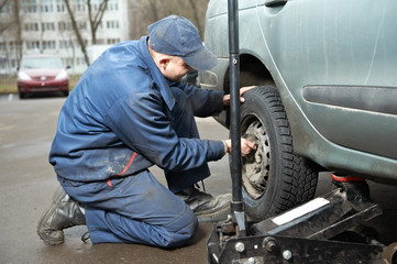 Obraz na płótnie Canvas machanic repairman at tyre fitting with car jack