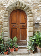 Fototapeta na wymiar drewniane drzwi z kamiennym łukiem do domu w stylu toskańskim