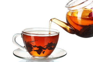 Glass teapot pouring black tea into cup isolated on white