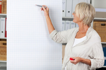 ältere frau schreibt am flipchart