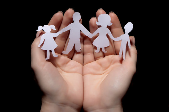 Paper Chain Family Protected In Cupped Hands On Black Background