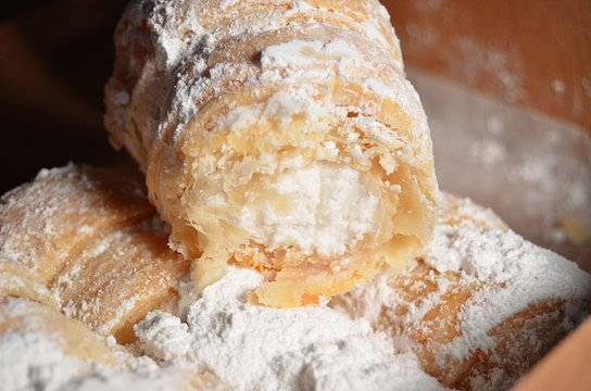 Cream Filled Pastries Covered In Powdered Sugar In A Brown Box