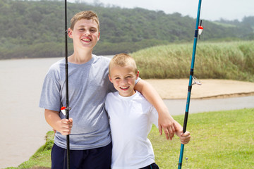 portrait of two little brothers fishing by the lake