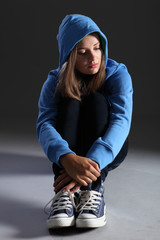 Blonde teenager girl alone and sad in blue hoodie