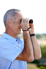senior man looking through binoculars