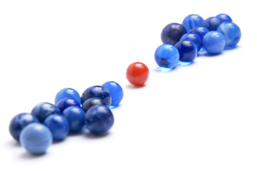 Red marble in the middle of blue marbles