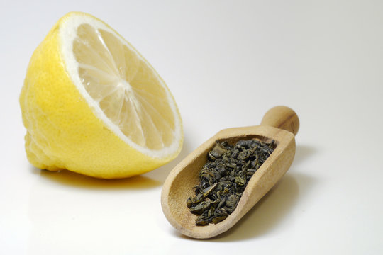 Gunpowder green tea on wooden laddle with lemon