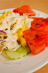 Salads, vegetables and fruit on a white plate